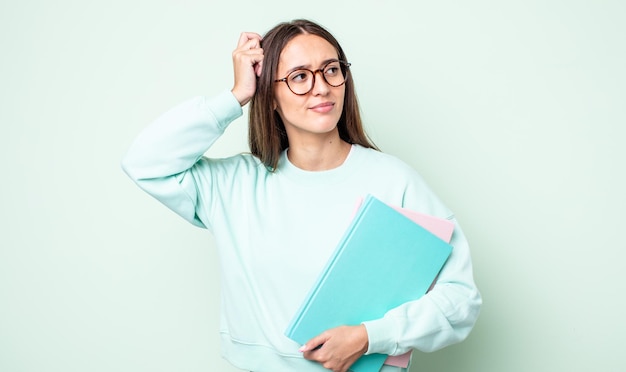 Giovane donna graziosa che sorride felicemente e sogna ad occhi aperti o dubita. studente universitario