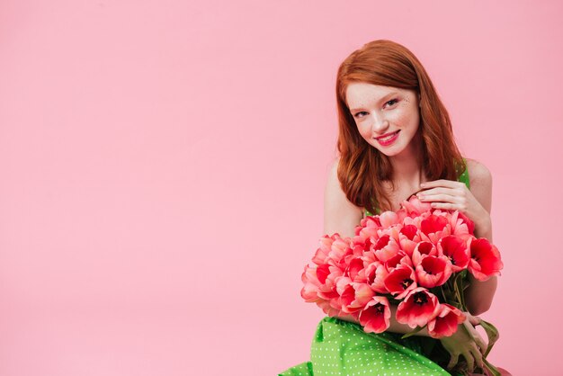 Giovane donna graziosa che tiene il mazzo di fiori