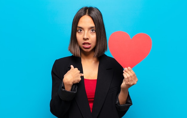 Giovane donna graziosa che tiene una carta del cuore