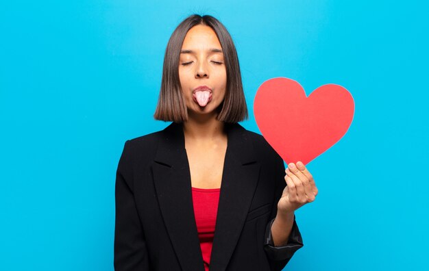 Giovane donna graziosa che tiene una carta del cuore