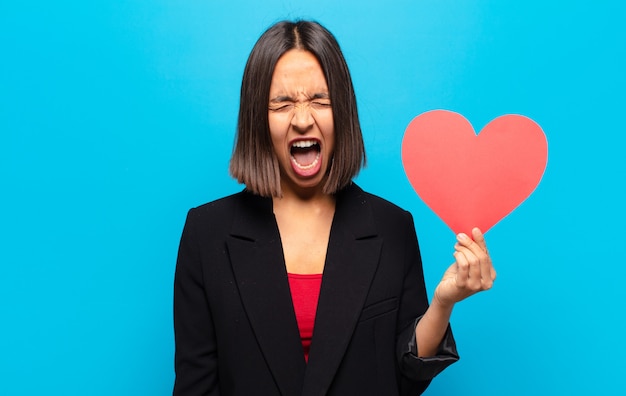 Giovane donna graziosa che tiene una carta del cuore