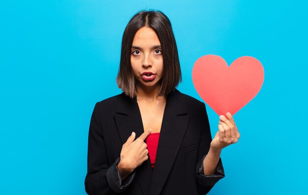 Giovane donna graziosa che tiene una carta del cuore