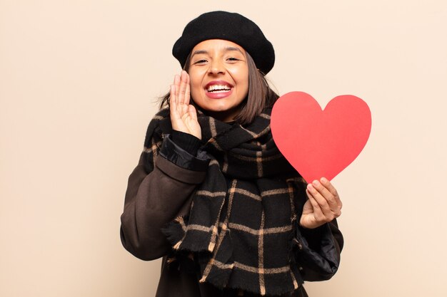 Giovane donna graziosa che tiene una carta del cuore