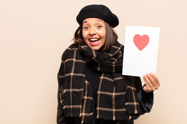 Giovane donna graziosa che tiene una carta del cuore