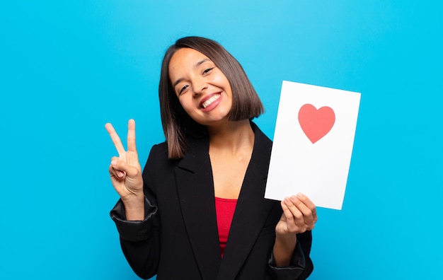 Giovane donna graziosa che tiene una carta del cuore