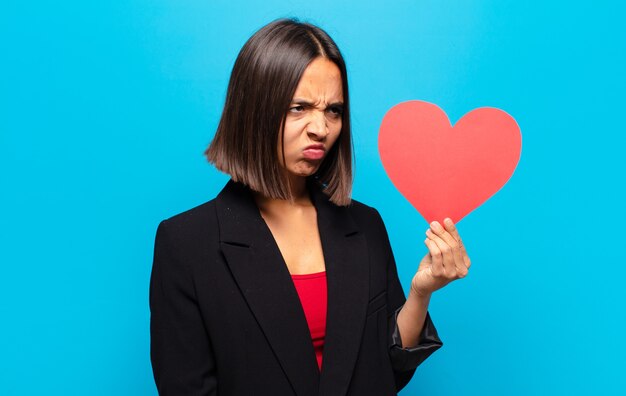 Giovane donna graziosa che tiene una carta del cuore