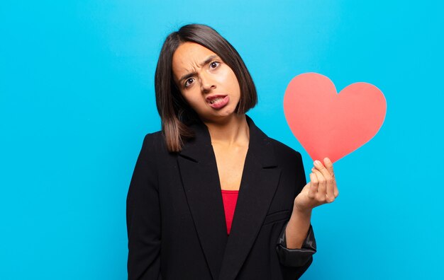 Giovane donna graziosa che tiene una carta del cuore