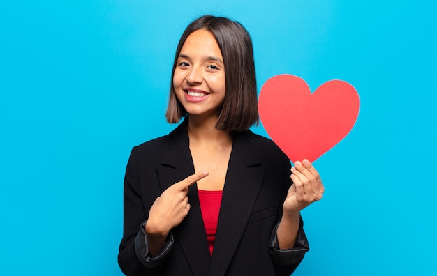 Giovane donna graziosa che tiene una carta del cuore