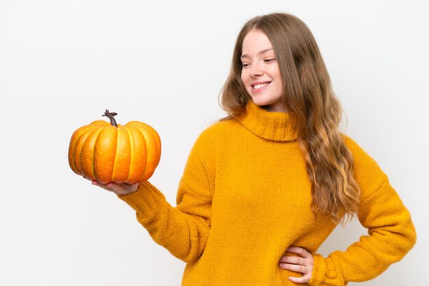 Giovane donna graziosa che tiene una zucca isolata su fondo bianco con l'espressione felice