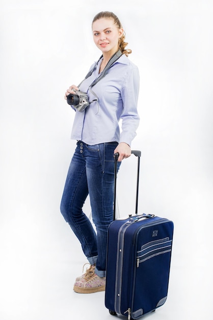 Giovane donna graziosa che viaggia con una grande valigia su sfondo bianco