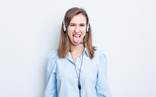 giovane donna graziosa con atteggiamento allegro e ribelle, scherzando e tirando fuori la lingua. concetto di telemarketing