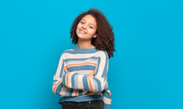 giovane donna graziosa con capelli afro e maglione a righe in posa sulla parete blu