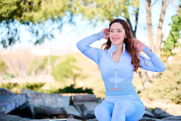 Giovane donna graziosa con gli occhi verdi in abito blu seduto nel parco cittadino