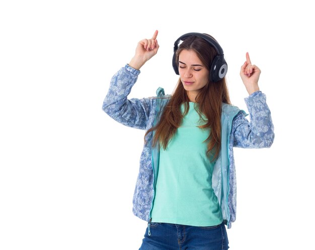 Giovane donna graziosa con i capelli lunghi in camicia che ascolta la musica in cuffia con gli occhi chiusi