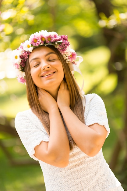 Giovane donna graziosa con i fiori in suoi capelli il giorno di molla soleggiato