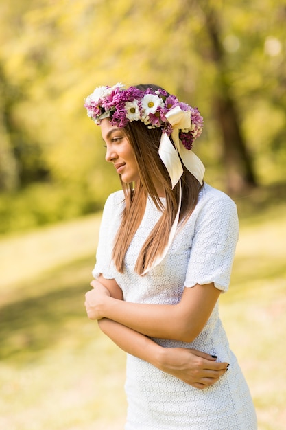 Giovane donna graziosa con i fiori in suoi capelli il giorno di molla soleggiato