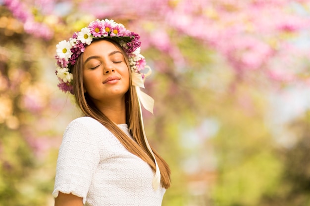 Giovane donna graziosa con i fiori in suoi capelli il giorno di molla soleggiato