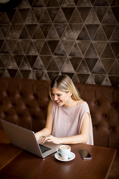 Giovane donna graziosa con il computer portatile nel caffè