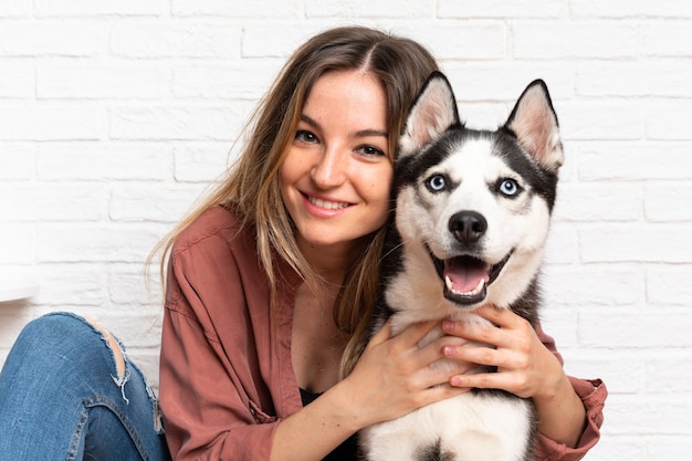 Giovane donna graziosa con il suo cane husky seduto sul pavimento al chiuso