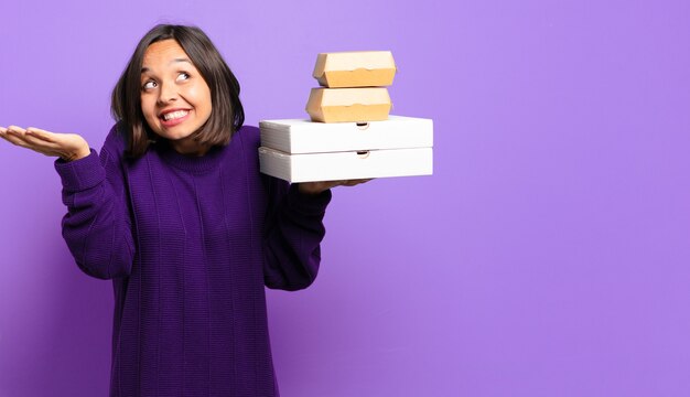 Giovane donna graziosa con scatole per alimenti. porta via il concetto di fast food