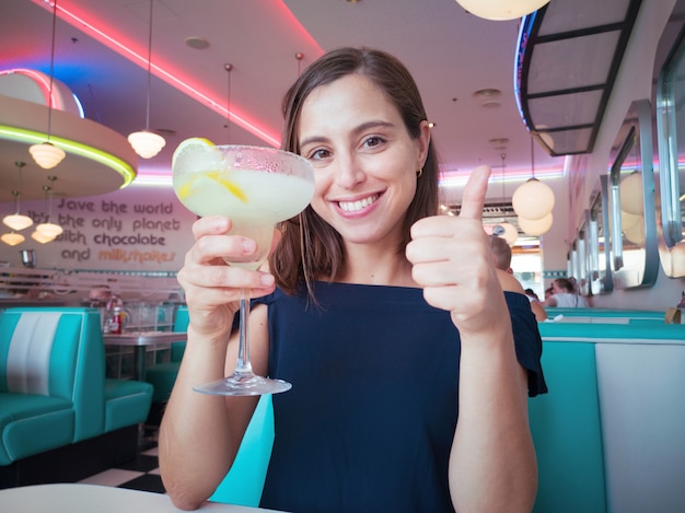 Giovane donna graziosa con un cocktail in un ristorante