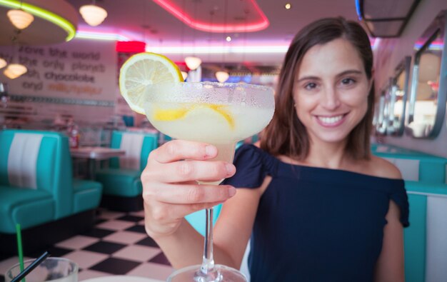 Giovane donna graziosa con un cocktail in un ristorante