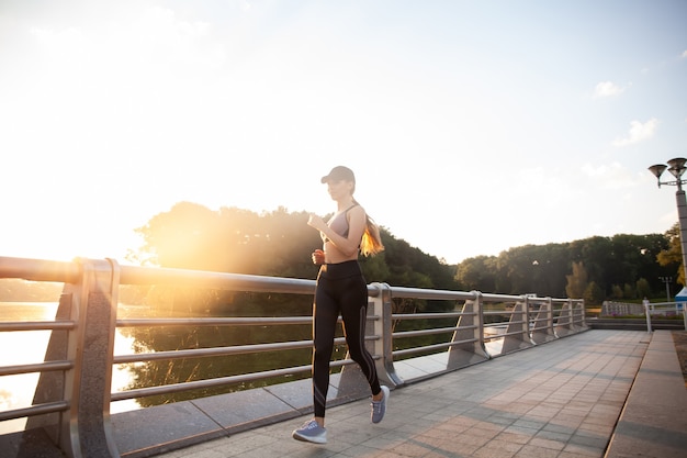 Giovane donna graziosa con un corpo snello perfetto che corre all'aperto. Fitness e concetto di corsa.