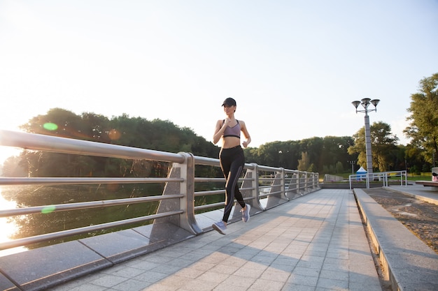 Giovane donna graziosa con un corpo snello perfetto che corre all'aperto. Fitness e concetto di corsa.