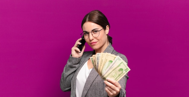 Giovane donna graziosa con un telefono e banconote in dollari. concetto di business