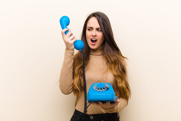 Giovane donna graziosa con un telefono vintage blu