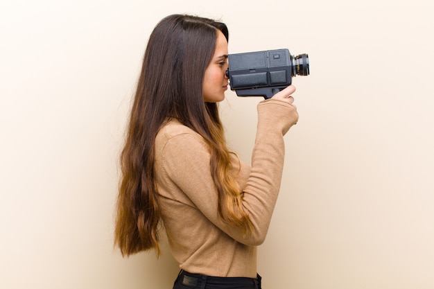 Giovane donna graziosa con una videocamera vintage