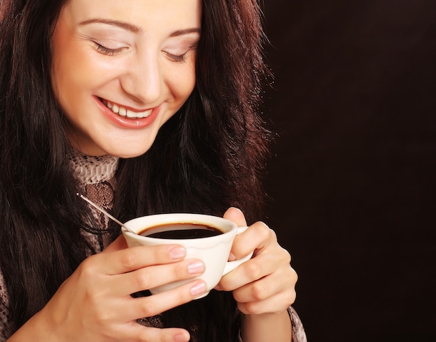 Giovane donna graziosa del brunette che beve caffè