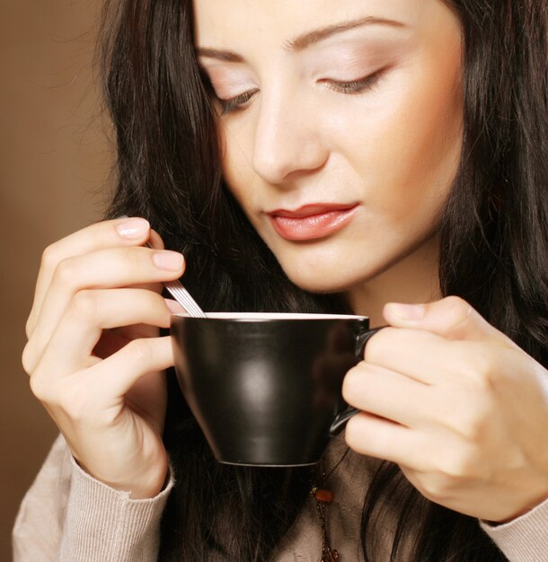 Giovane donna graziosa del brunette che beve caffè