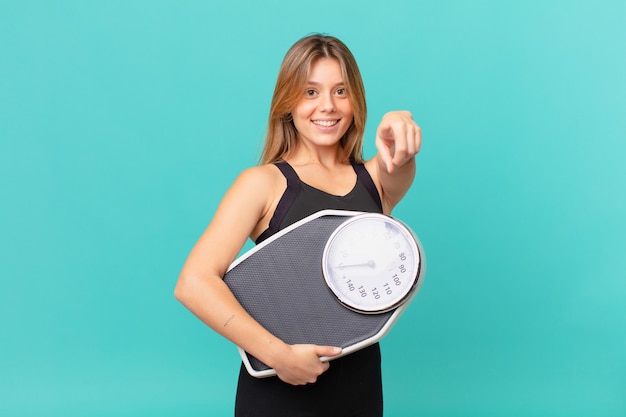 Giovane donna graziosa di forma fisica che indica alla macchina fotografica che sceglie voi