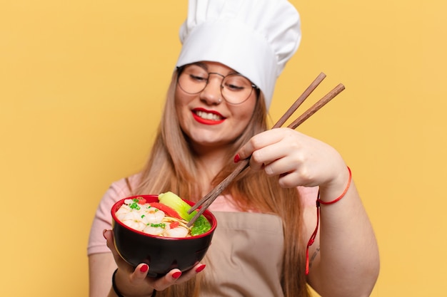 Giovane donna graziosa. espressione felice e sorpresa. chef che cucina il concetto di noodles