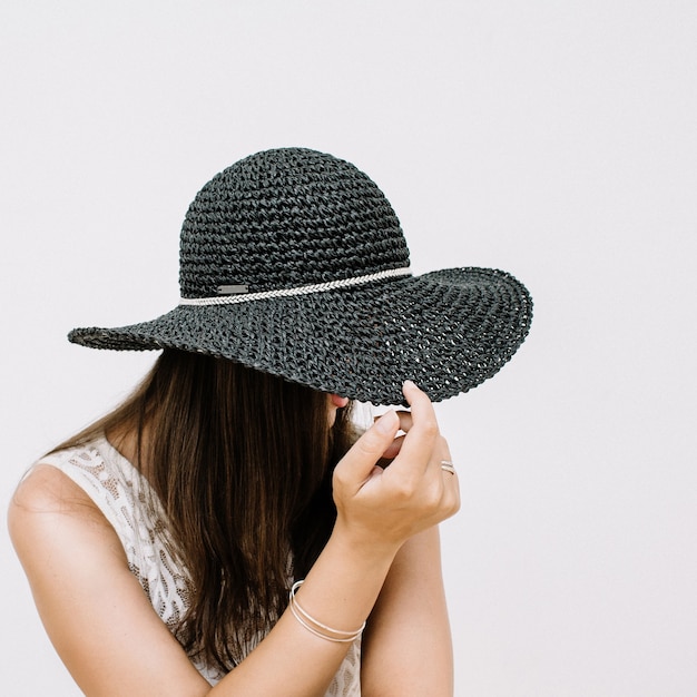 Giovane donna graziosa in abito bianco con cappello nero