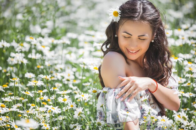 Giovane donna graziosa nel campo della camomilla. Bella ragazza con fiori