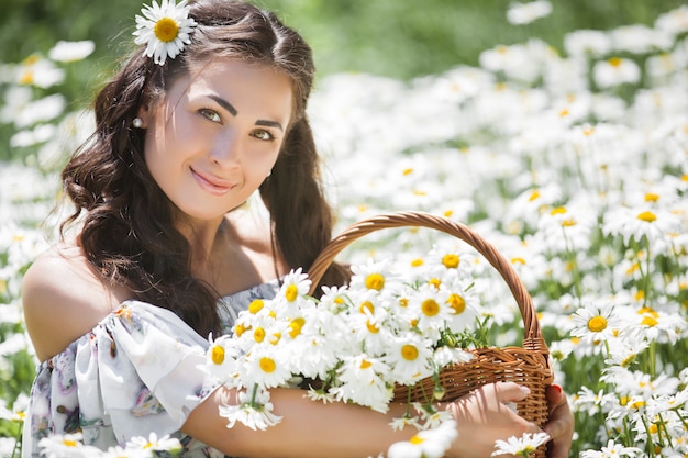 Giovane donna graziosa nel campo della camomilla. Bella ragazza con fiori