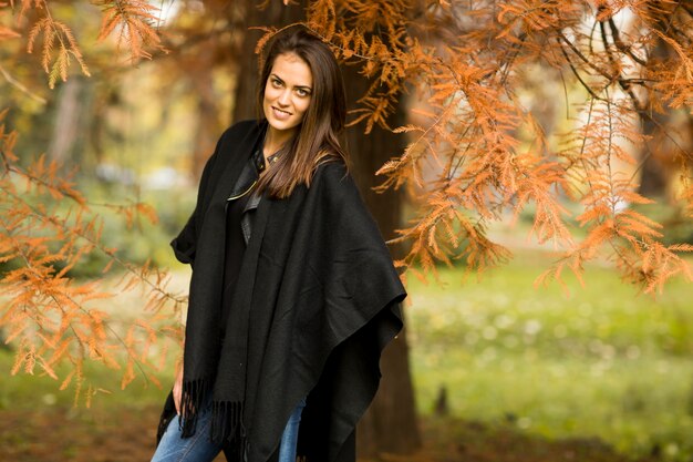 Giovane donna graziosa nel parco di autunno