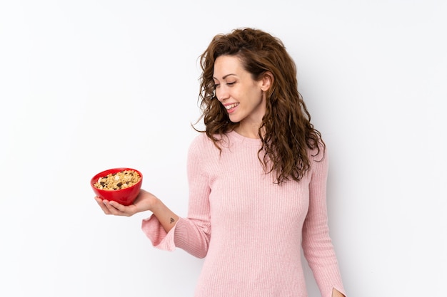 Giovane donna graziosa sopra isolata tenendo una ciotola di cereali