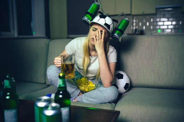 Giovane donna guarda la partita di calcio in tv di notte.