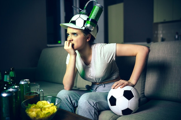 Giovane donna guarda la partita di calcio in tv di notte.