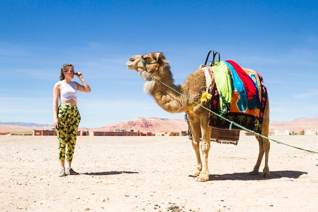 Giovane donna guardando un cammello nel deserto