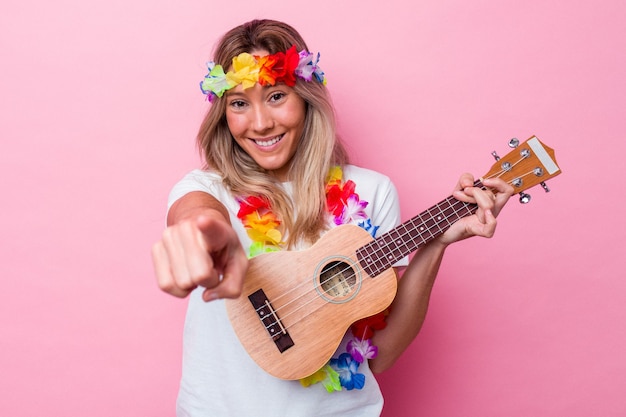 Giovane donna hawaiana che gioca un ukulele isolato su sfondo rosa