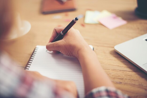 Giovane donna hipster che scrive e lavora sul posto di lavoro