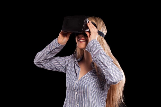 Giovane donna immersa in un videogioco interattivo di realtà virtuale che fa gesti su sfondo nero