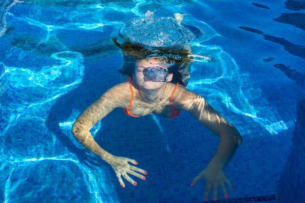 Giovane donna immersa sotto l'acqua in piscina.