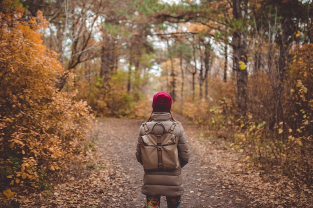 Giovane donna in abbigliamento casual in piedi nella foresta autunnale.