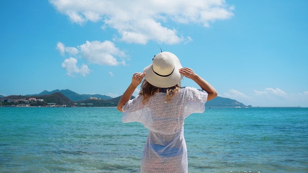 Giovane donna in abiti bianchi rinfrescante presso la spiaggia dell'oceano, China