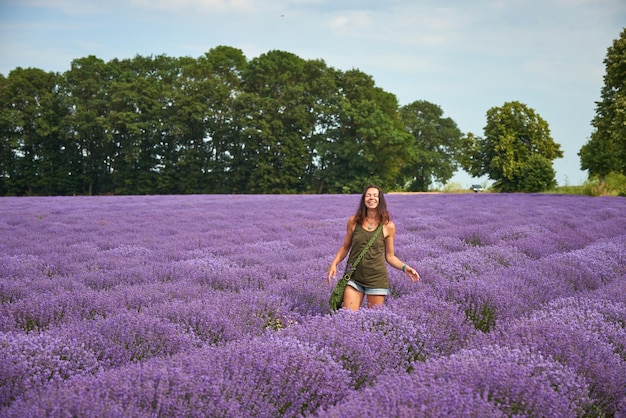 Giovane donna in abiti casual cammina attraverso un campo di lavanda in fiore